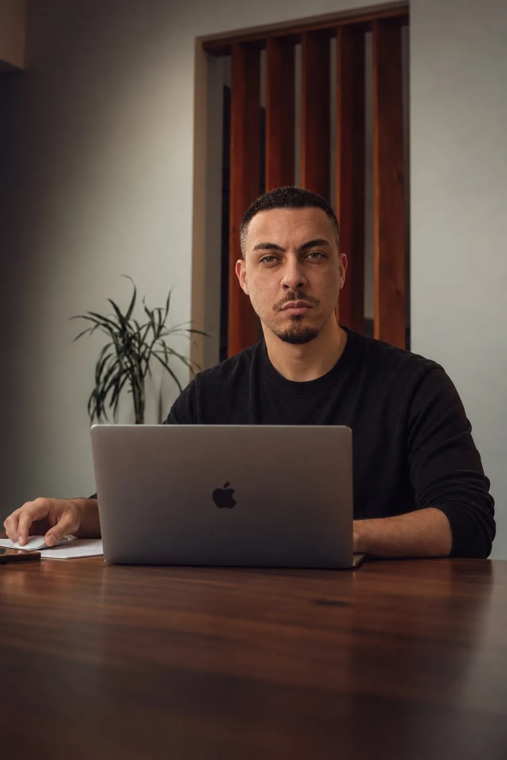 Cristhian sentado diante de um notebook, olhando para a câmera